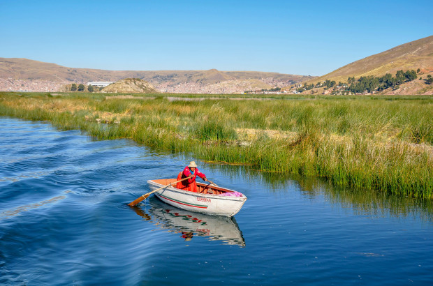 The Uros Islands of Lake Titicaca in Peru Peruvian woman rowing to the Uros islands in Lake Titicaca