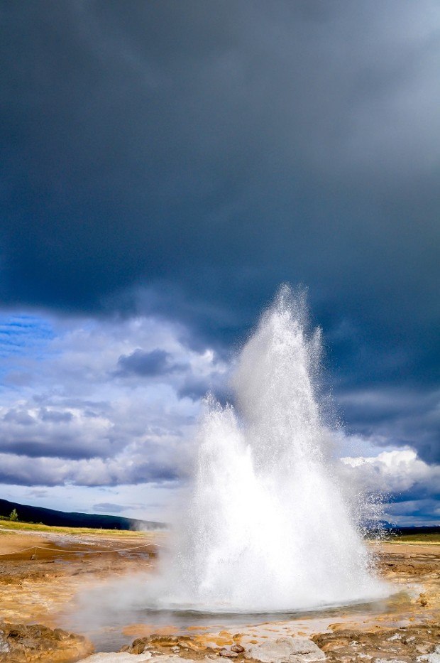 Strokkur geyser, mid-eruption, against a dark sky