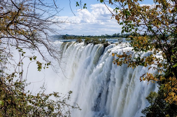 Victoria Falls is Gorges (and Wet)! Approaching The Victoria Falls Livingstone, Zambia side. The Zambezi River plunges over a rock ledge into the gorge below.