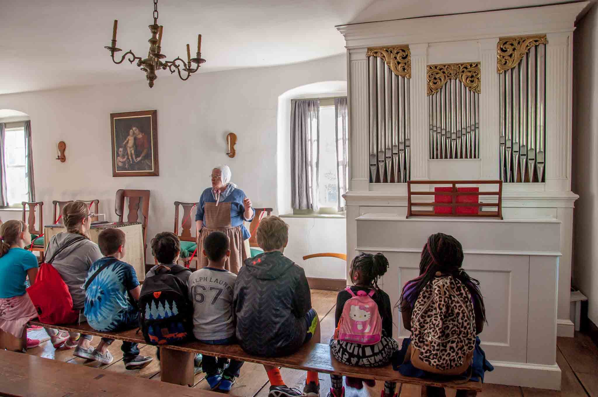 Group of children listening to a lecture in the chapel by an organ