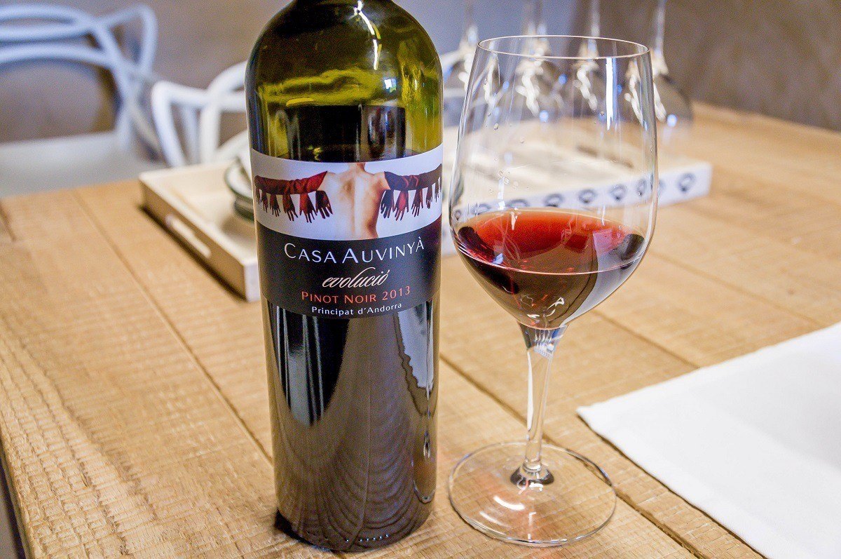 Glass and bottle of wine at Casa Auvinya winery on wood table