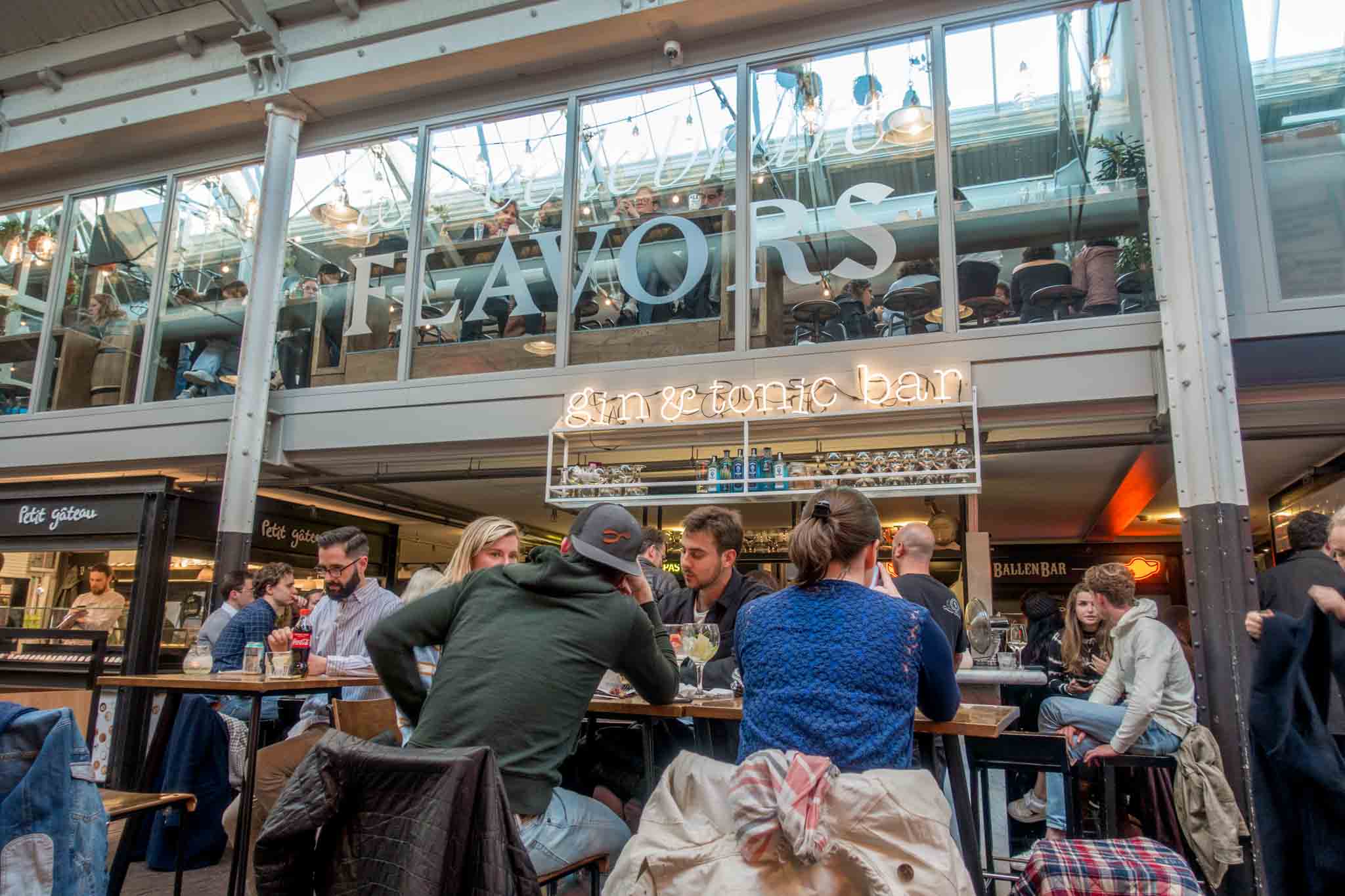People sitting at the Gin & Tonic Bar in Foodhallen. A visit here is one of my favorite Amsterdam things to do.