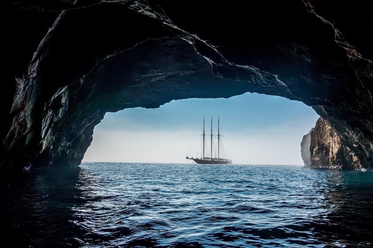 Ship seen through the arch of a cave