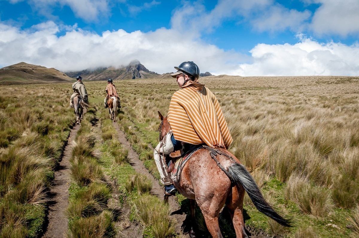 Three people riding horses through the Avenue of the Volcanoes in Ecuador