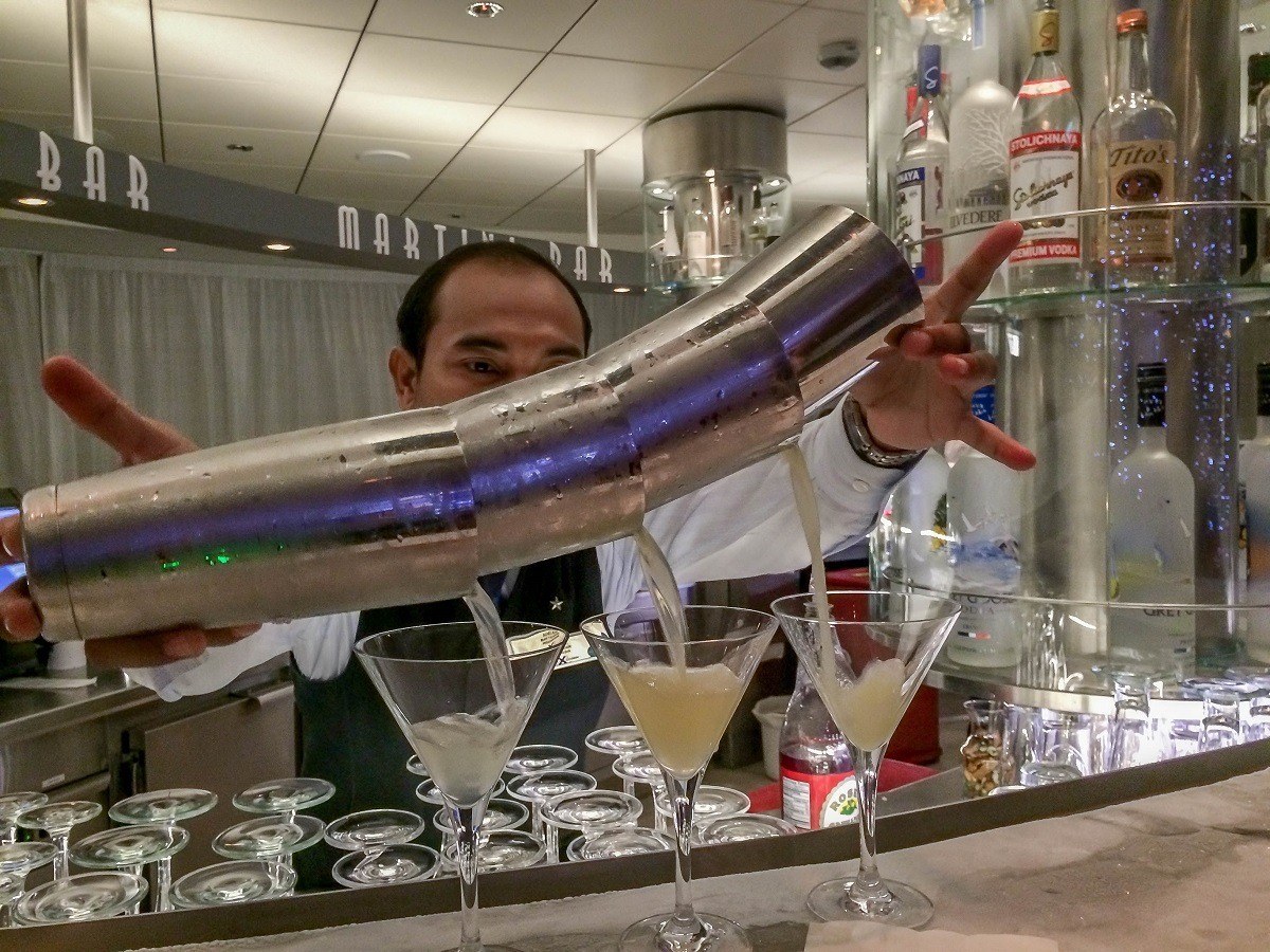 Bartender pouring cocktails into martini glasses