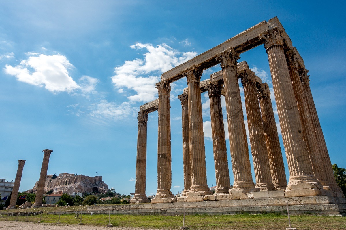 Large ruined columns of the Temple of Olympian Zeus with the Acropolis hill in the distance