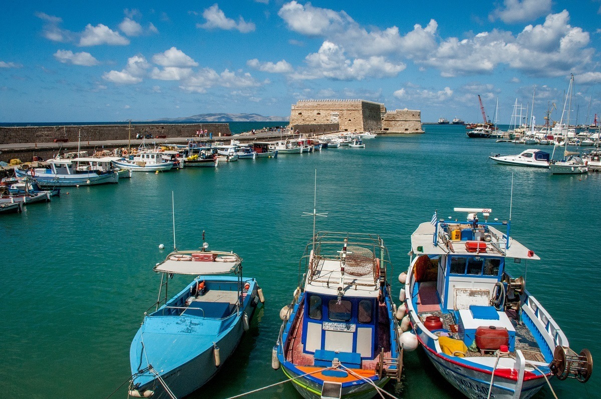 Colorful boats and stone fortress in the harbor of Heraklion