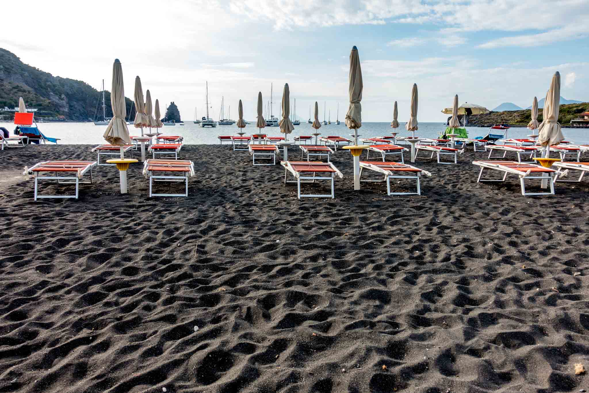 Chairs on black sand beach on Vulcano