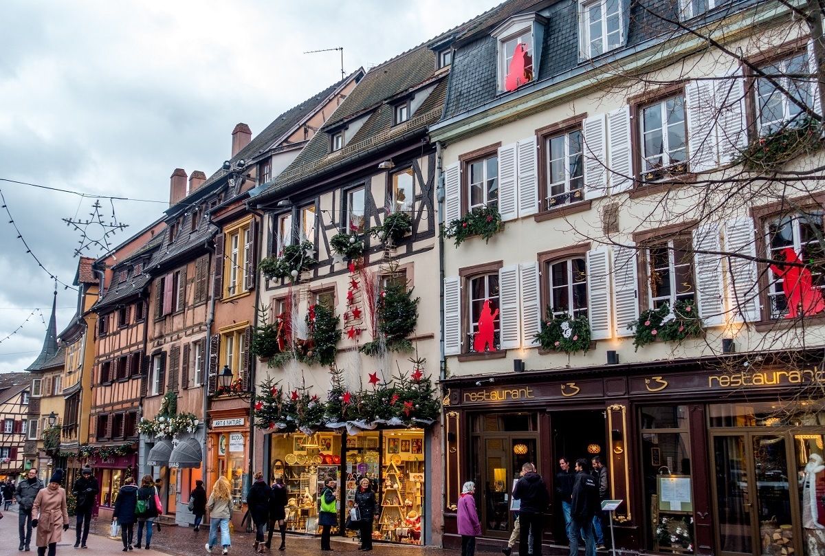 People walking by stores decorated for the Christmas holidays