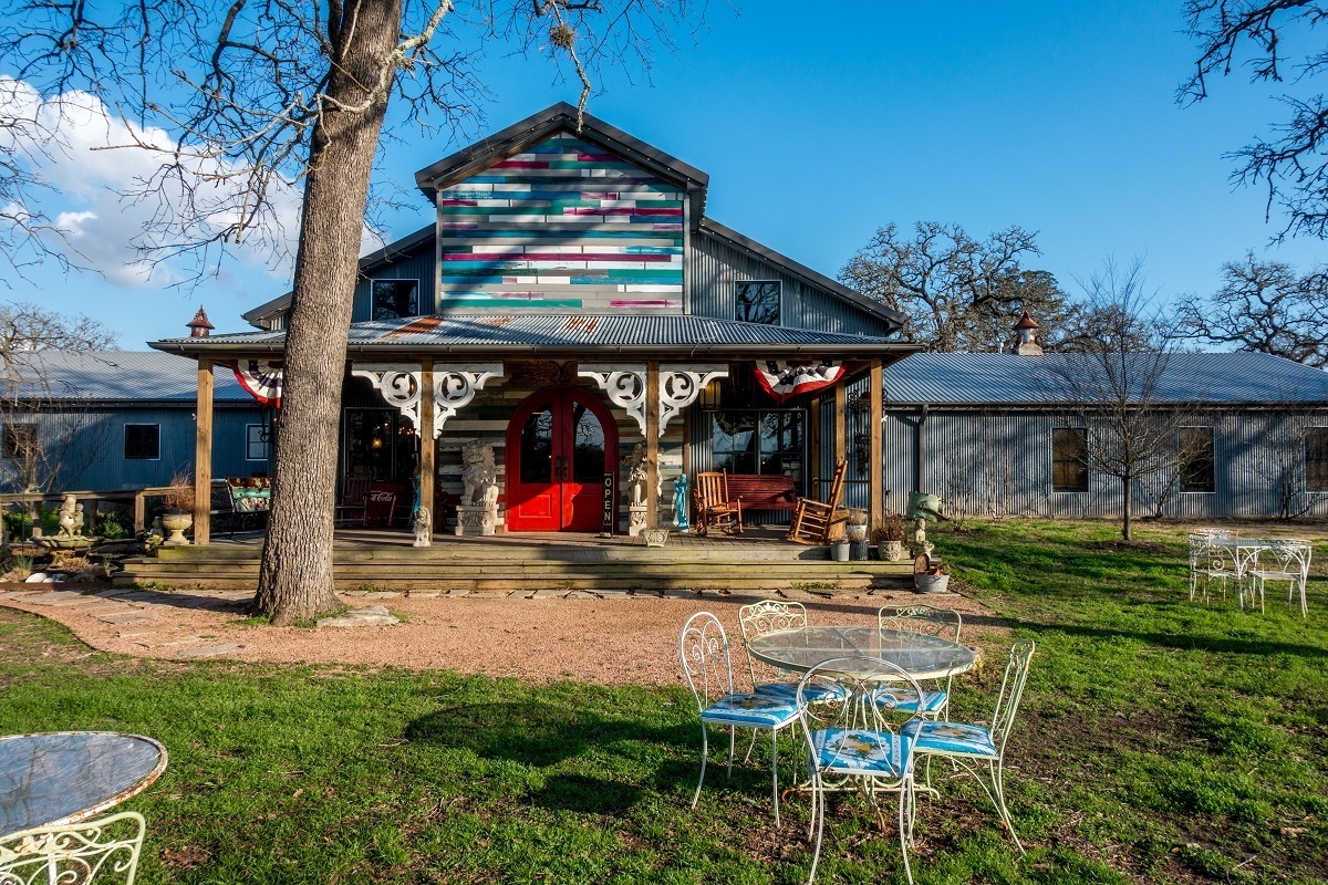 Exterior of barn-like building with table and chairs in yard, Junk Gypsy