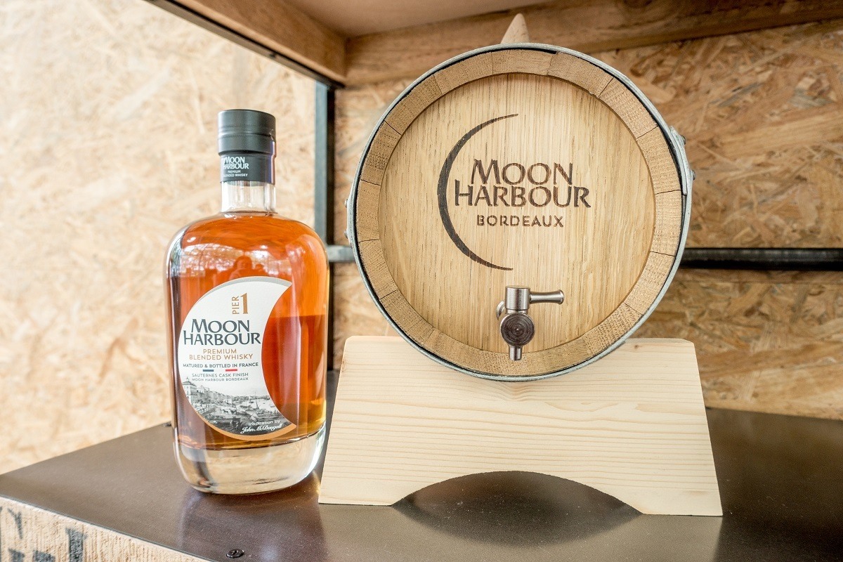Whiskey bottle on shelf next to mini-barrel from Moon Harbour Distillery