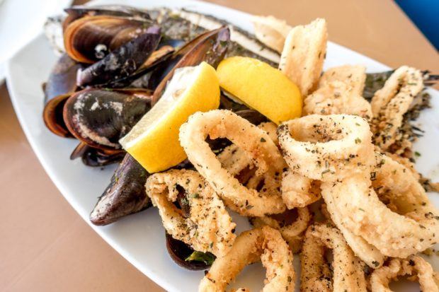 Mussels, calamari, lampuki fish, and lemon on a plate in Maraxlokk, Malta