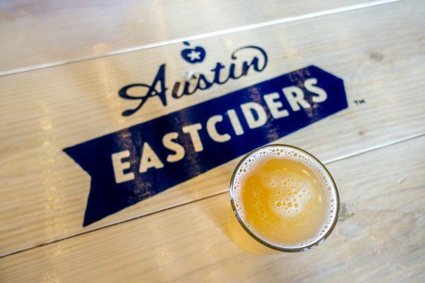 Pint of cider on table with Austin Eastciders logo. Visiting Eastciders is what to do in Austin Texas for cider lovers.