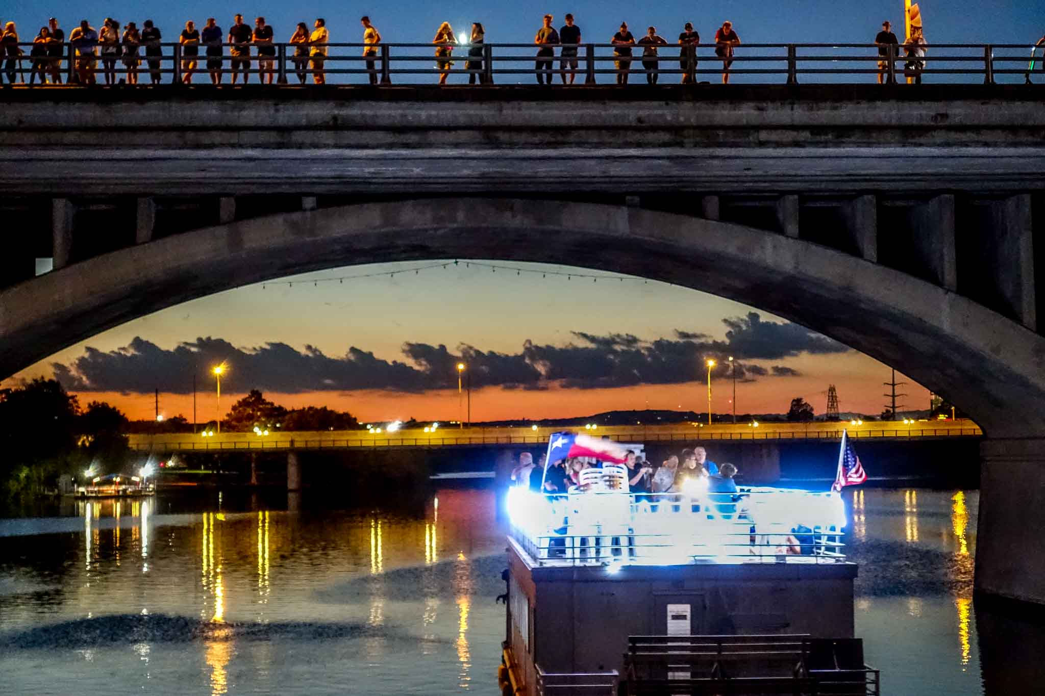 Boat under bridge with people standing above