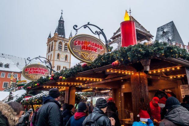 Food stalls covered with garland and lights on an overcast day at the Trier Christmas market in Germany