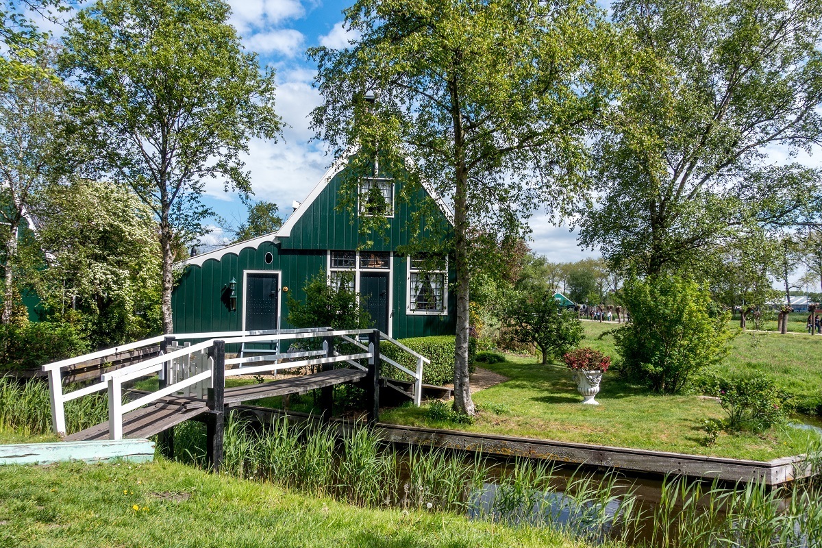 A green traditional Zaans house with a bridge over the canal as seen on a Zaanse Schans tour