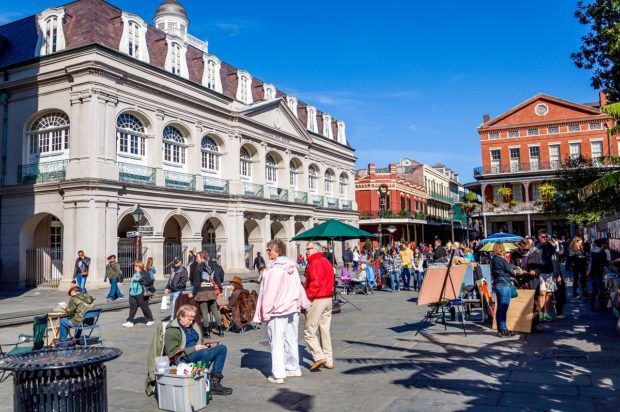 People looking at art work and walking around Jackson Square in front of the Cabildo in the city of New Orleans
