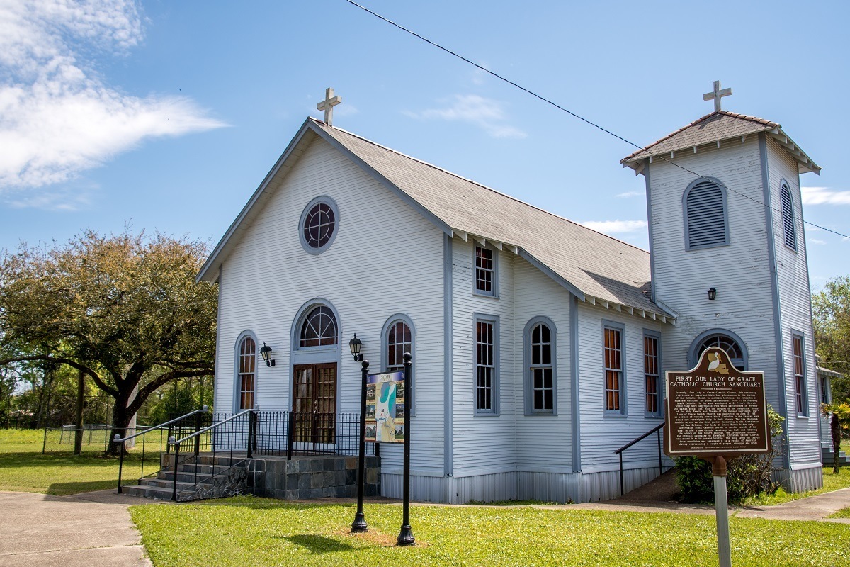 White exterior of a small country church in Louisiana with sign about its history