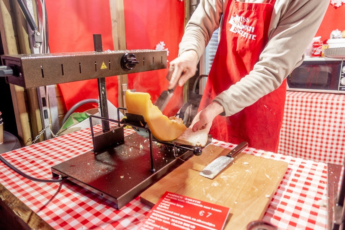 Person serving raclette, melted cheese on bread