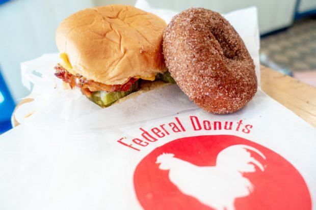 Chicken sandwich and donut on a table with the red Federal Donuts logo. A stop provides an excellent, quick meal if you're seeing Philadelphia in a day.