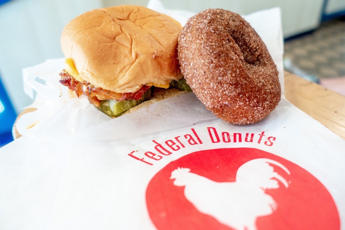 Chicken sandwich and donut on a table with the red Federal Donuts logo. A stop provides an excellent, quick meal if you're seeing Philadelphia in a day.