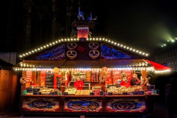 One of the Alsatian food stands selling pretzels near the Cathedral is lit up at night at the Strasbourg France Christmas market