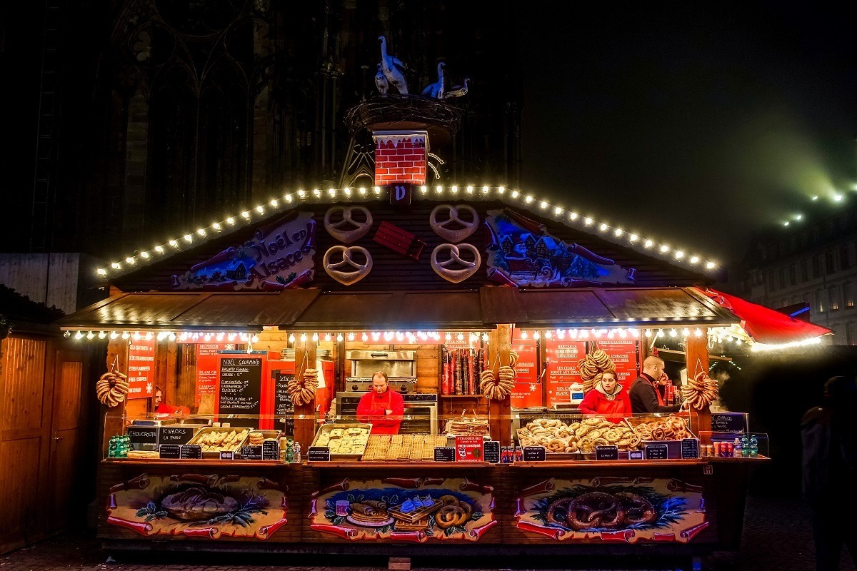 One of the Alsatian food stands selling pretzels near the Cathedral is lit up at night at the Strasbourg France Christmas market