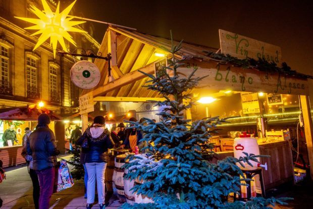 Chalet lit up at night selling Alsatian mulled wine in Palais Rohan in Strasbourg, one of the best Xmas markets in Europe