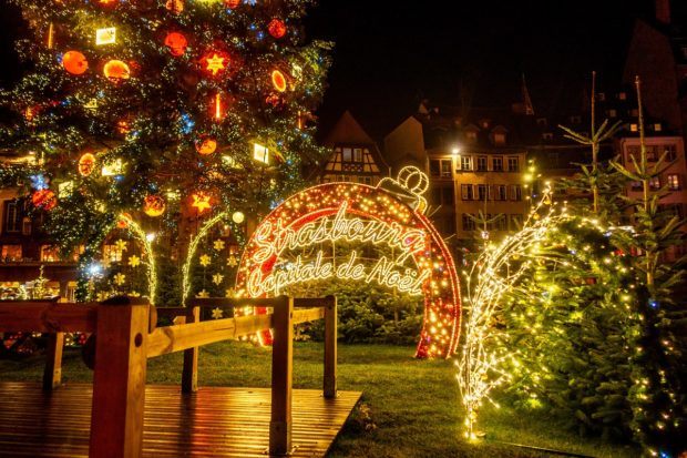 Part of the Strasbourg Christmas tree and "Capitale de Noel" sign lit up at night in Place Kleber