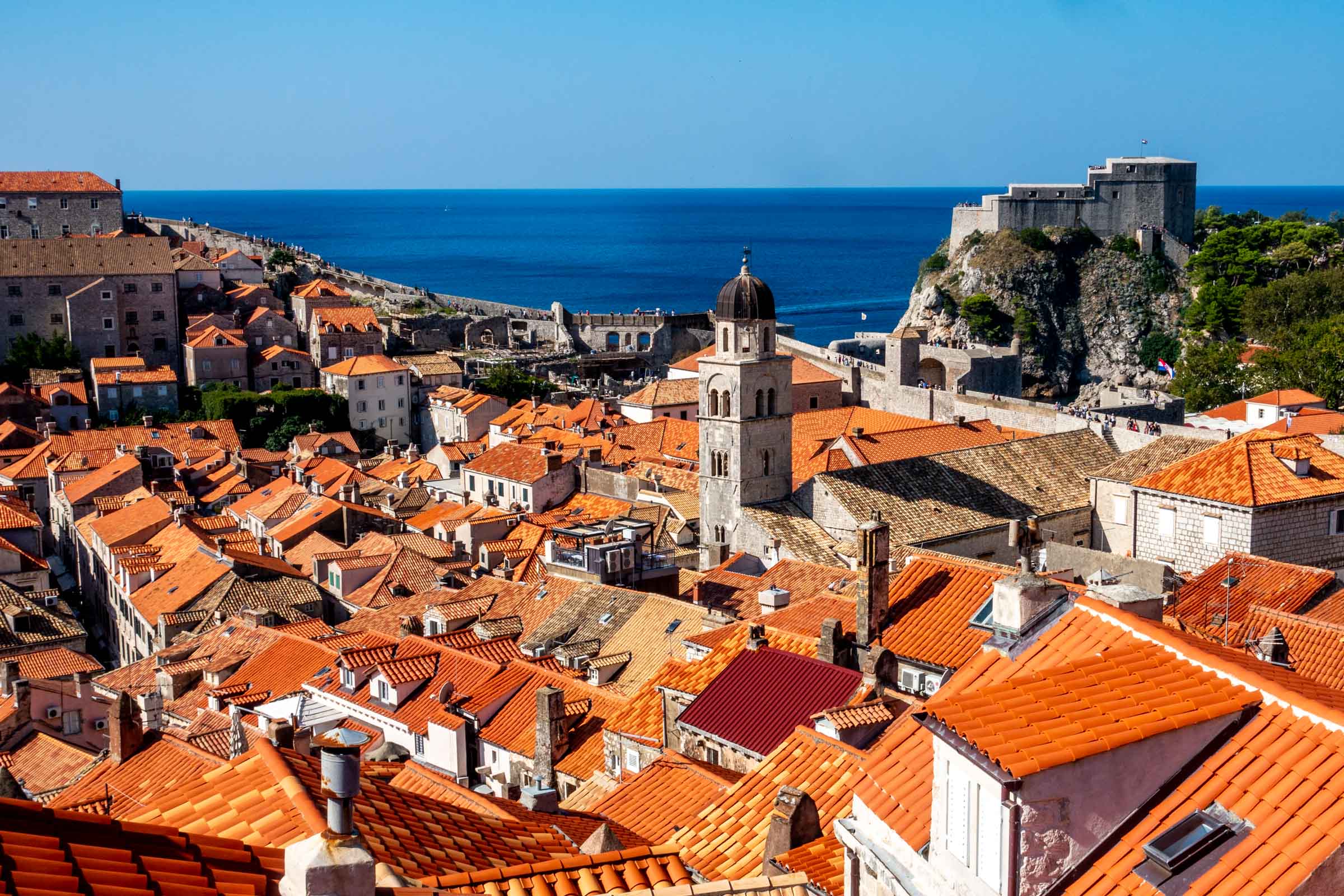 View of red roofs, bell tower, and ancient Dubrovnik city walls from another portion of the walls