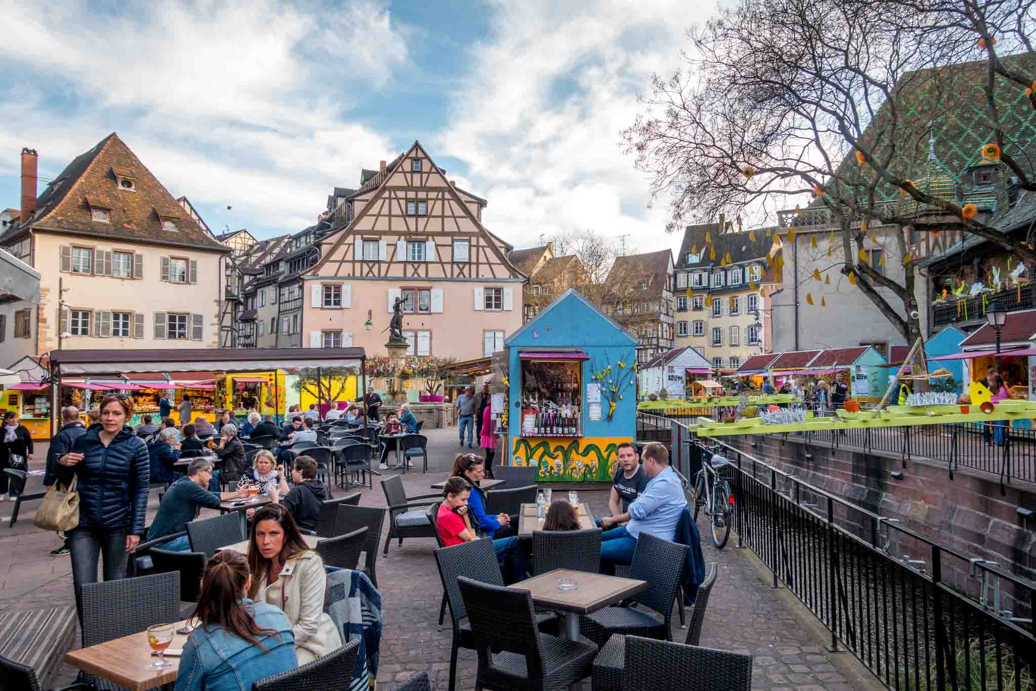 People having drinks outdoors with a spring market in the background