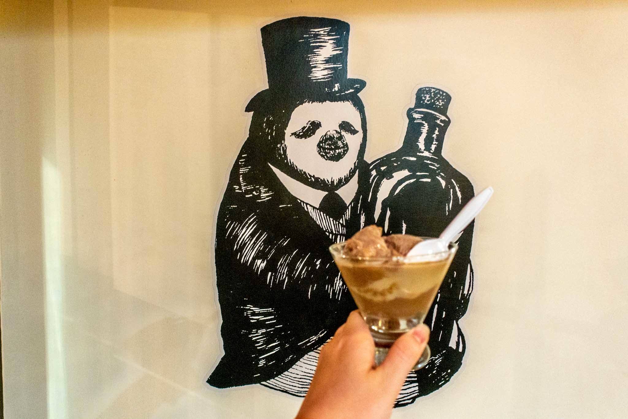 Dish of ice cream in front of a drawing of a penguin holding a bottle