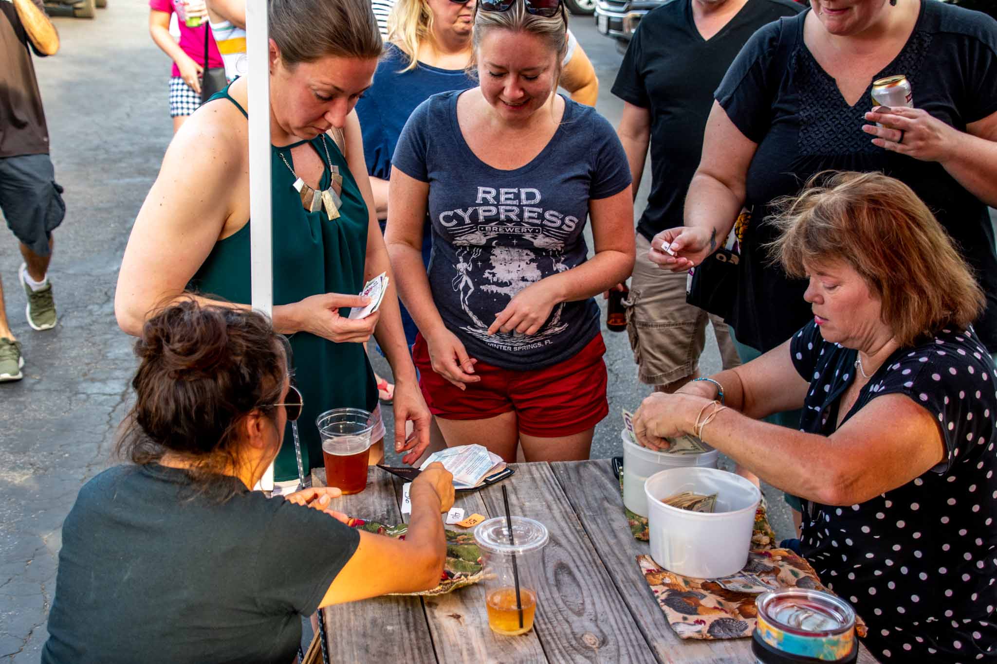 People buying tickets from women seated at a picnic table