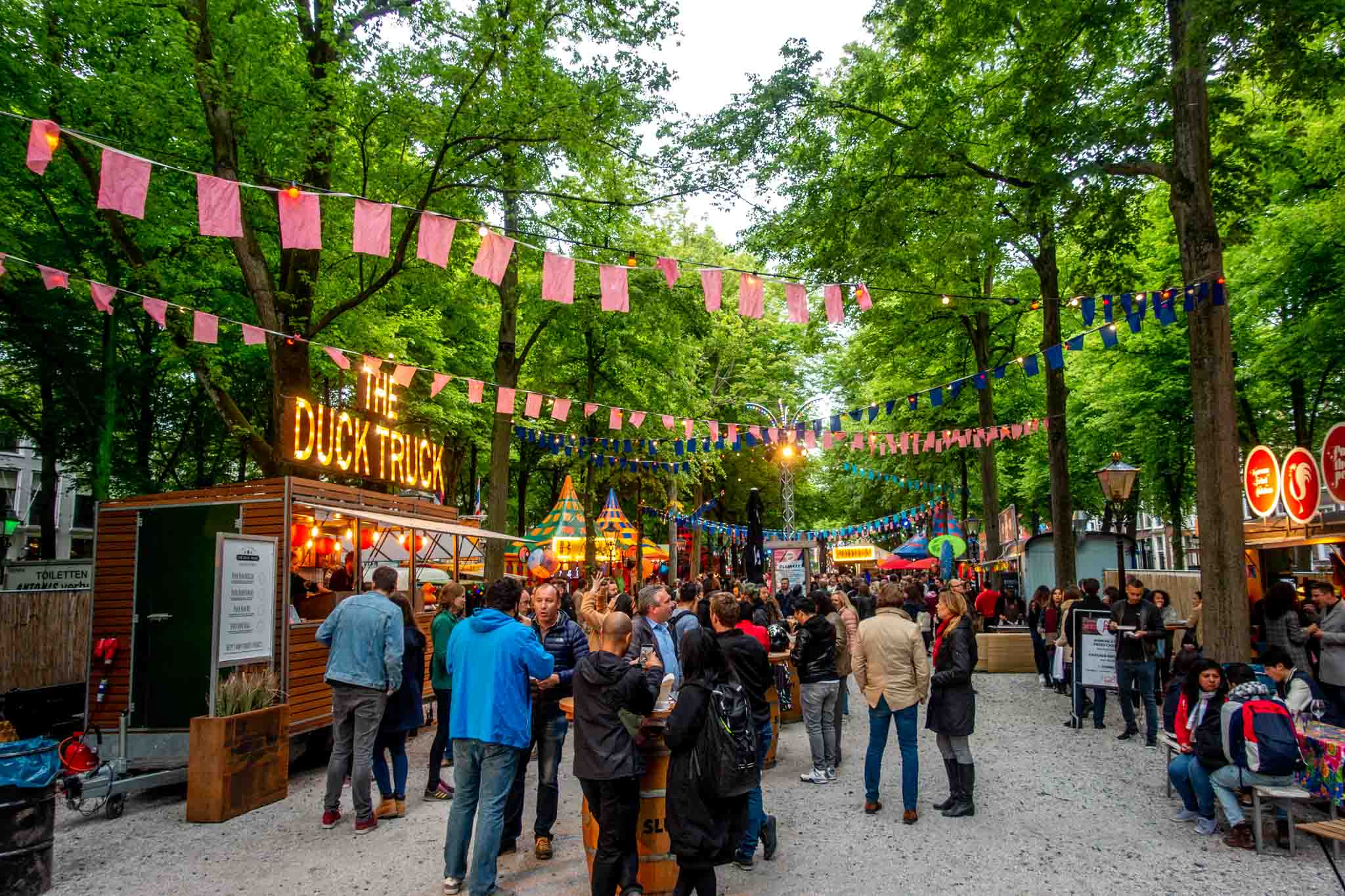 People at a street food fair at a tree-lined park