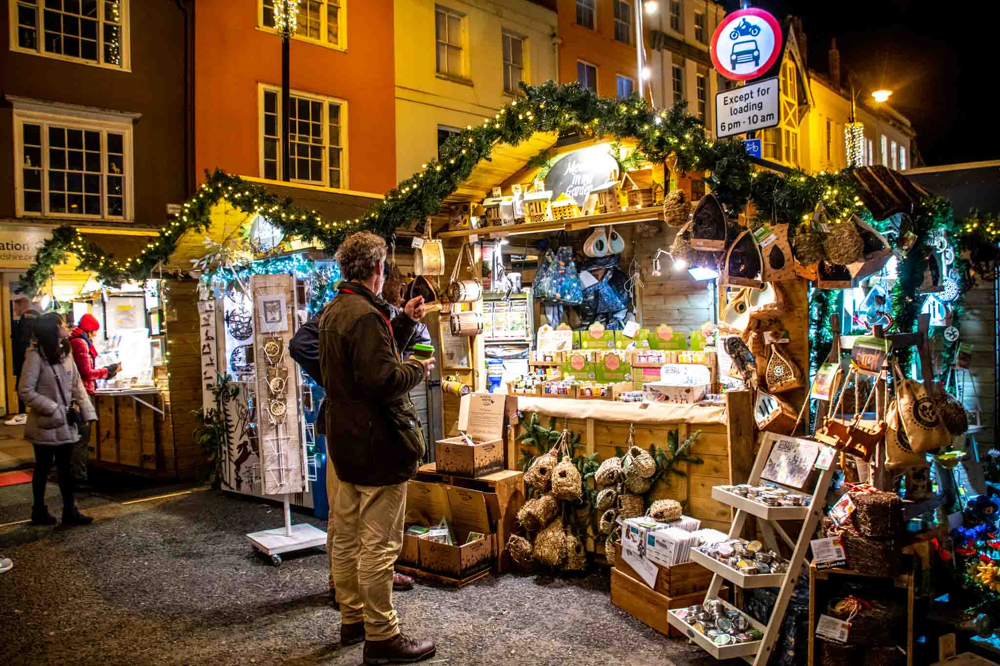 Shoppers in front of wooden chalets selling Christmas gifts