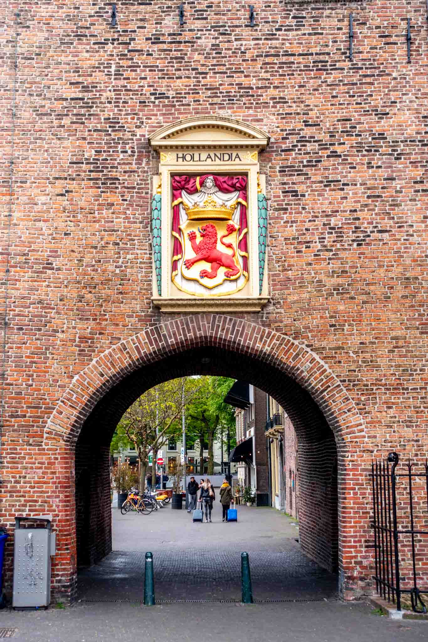 Coat of arms and sign for "Hollandia" hanging over a brick city gate