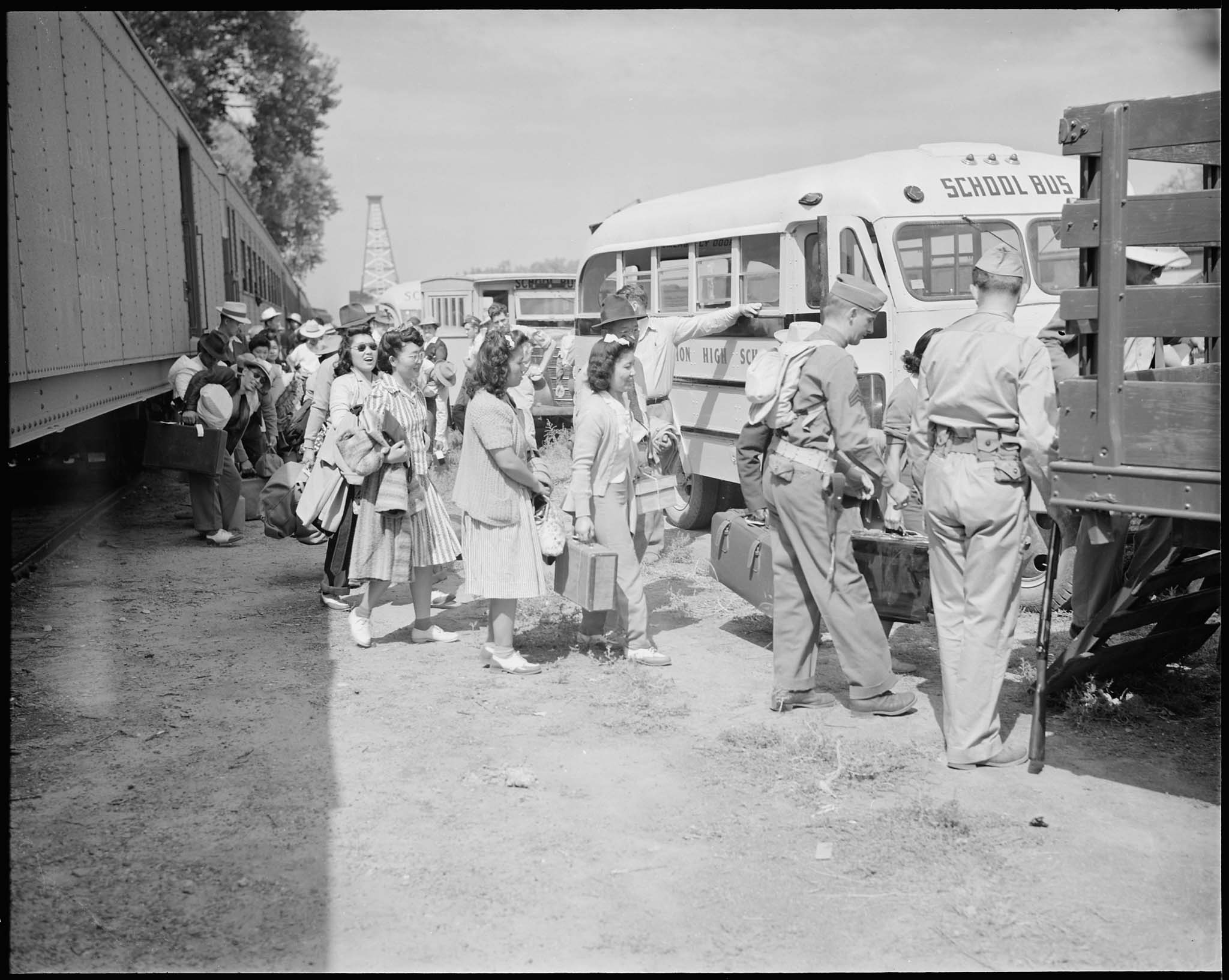 Japanese Americans leaving trains and boarding trucks and buses to the Granada Relocation Center